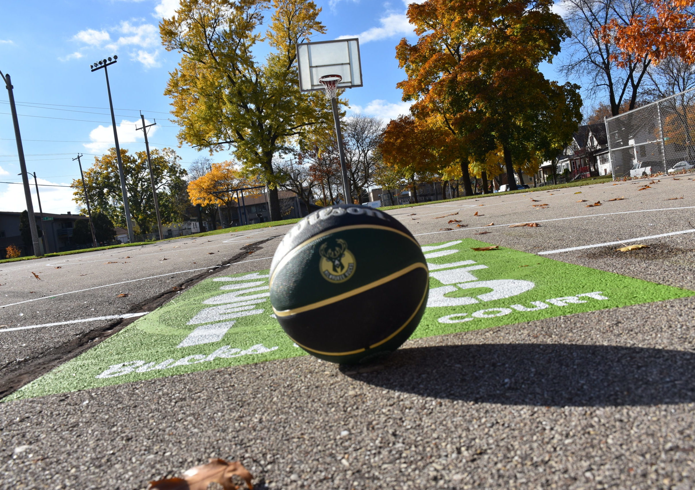 a basketball with a Bucks logo on an outdoor basketball court
