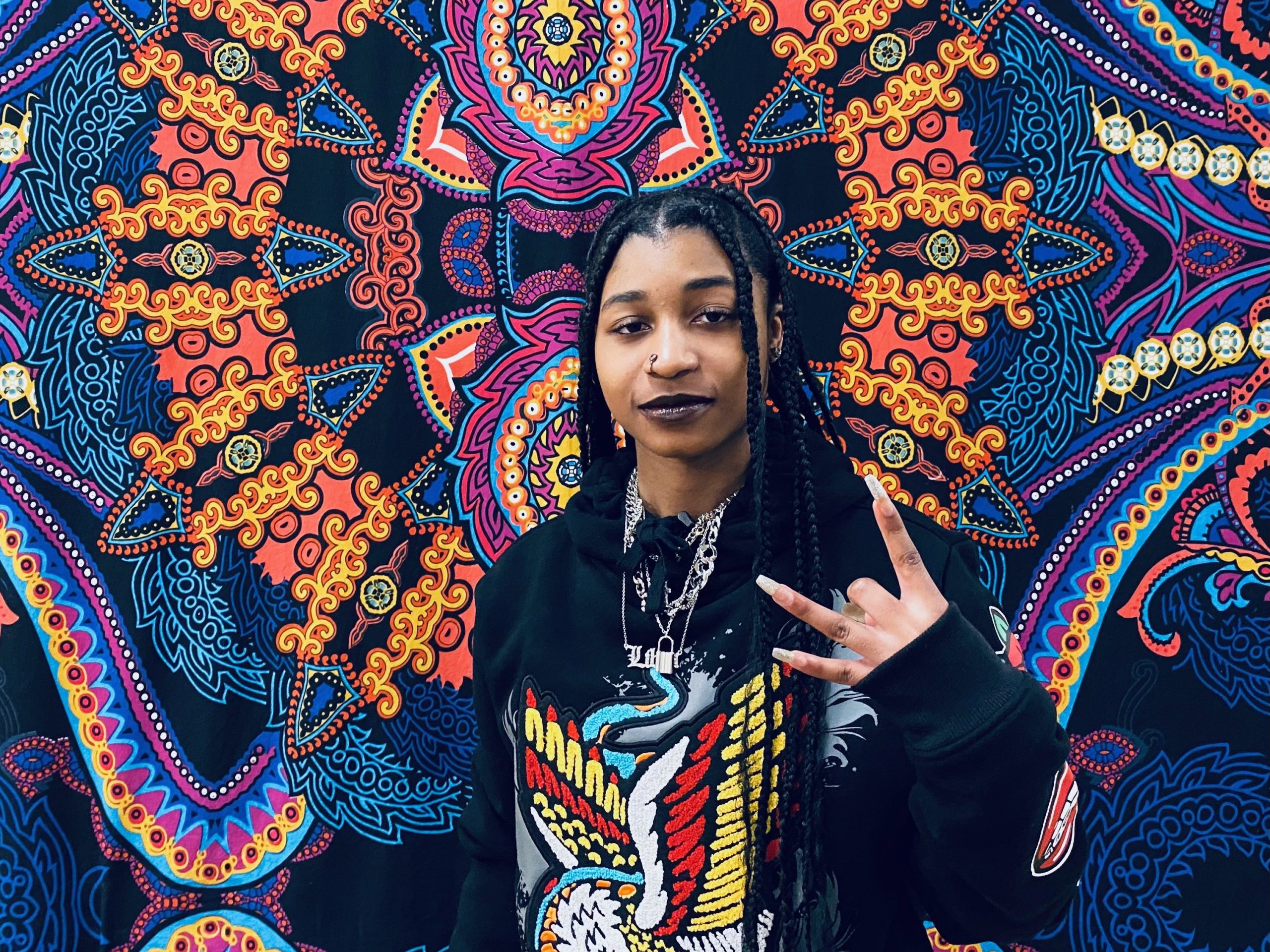 A young Black teen standing in front of a colorful mural