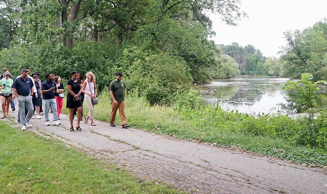 group of people walking along a path next to a pond